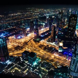 A stunning aerial view of Dubai's illuminated skyline at night, showcasing its modern architecture and busy roads.
